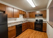 Thumbnail 14 of 25 - A kitchen with wooden cabinets and black appliances. Fargo, ND Park Place Apartments