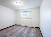 Thumbnail 41 of 43 - A room with a window and a carpeted floor. Fargo, ND Islander Apartments