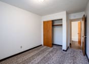 Thumbnail 40 of 43 - A room with a carpeted floor and a brown door. Fargo, ND Islander Apartments