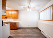 Thumbnail 38 of 43 - A kitchen with wooden cabinets and a ceiling fan. Fargo, ND Islander Apartments