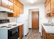 Thumbnail 37 of 43 - A kitchen with wooden cabinets and a white stove top oven. Fargo, ND Islander Apartments