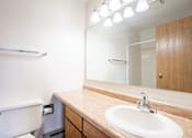 Thumbnail 8 of 10 - A bathroom with a sink, mirror, and toilet. Fargo, ND Hawthorn Apartments