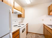 Thumbnail 5 of 10 - A kitchen with a white refrigerator and white stove. Fargo, ND Hawthorn Apartments