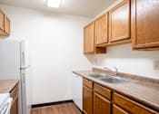 Thumbnail 9 of 15 - A kitchen with a white refrigerator and brown cabinets. Fargo, ND Summerfield Apartments