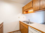 Thumbnail 6 of 10 - A kitchen with wooden cabinets and a white countertop. Fargo, ND Hawthorn Apartments