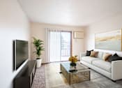 Thumbnail 1 of 10 - A living room with a white couch, a flat screen TV, a coffee table, and a painting on the wall. Fargo, ND Hawthorn Apartments