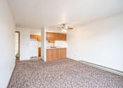 Thumbnail 4 of 10 - A room with a ceiling fan and a kitchen area in the background. Fargo, ND Hawthorn Apartments