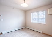 Thumbnail 16 of 20 - A room with a window and a carpeted floor. Fargo, ND East Bridge Apartments
