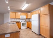 Thumbnail 14 of 20 - A kitchen with wooden cabinets and white appliances. Fargo, ND East Bridge Apartments