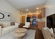 Thumbnail 1 of 18 - A modern living room with a white couch, wooden coffee table, and a painting on the wall.