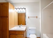 Thumbnail 13 of 14 - A white toilet sits next to a sink in a bathroom. Fargo, ND Crown Court 2 Apartments