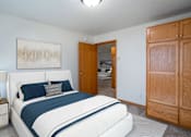 Thumbnail 5 of 14 - A bedroom with a large bed and a wooden wardrobe. Fargo, ND Crown Court Apartments