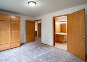 Thumbnail 10 of 14 - A room with a carpeted floor and a wooden door. Fargo, ND Crown Court 2 Apartments