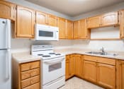 Thumbnail 8 of 14 - A kitchen with wooden cabinets and a white refrigerator. Fargo, ND Crown Court 2 Apartments
