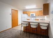 Thumbnail 3 of 14 - A kitchen with white appliances and wooden cabinets. Fargo, ND Crown Court Apartments