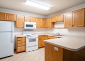 Thumbnail 7 of 14 - A kitchen with wooden cabinets and white appliances. Fargo, ND Crown Court 2 Apartments