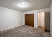 Thumbnail 9 of 14 - A room with a carpeted floor and a brown door. Fargo, ND Park Terrace Apartments