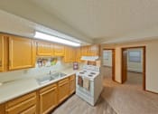 Thumbnail 7 of 7 - A kitchen with wooden cabinets and a white stove top oven.