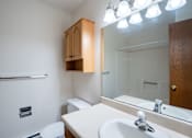 Thumbnail 11 of 14 - A bathroom with a toilet, sink, mirror, and cabinet. West Fargo, ND Clearview Apartments