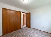 Thumbnail 8 of 14 - A room with a carpeted floor and two wooden doors. West Fargo, ND Clearview Apartments