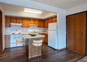 Thumbnail 3 of 14 - A kitchen with wooden cabinets and a white fridge. West Fargo, ND Clearview Apartments