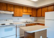 Thumbnail 6 of 14 - A kitchen with a white stove and white refrigerator. West Fargo, ND Clearview Apartments