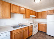 Thumbnail 8 of 28 - A kitchen with wooden cabinets and white appliances. West Fargo, ND Sheyenne Terrace Townhomes