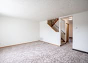 Thumbnail 7 of 28 - A living room with a carpeted floor and a staircase leading to another room. West Fargo, ND Sheyenne Terrace Townhomes