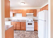 Thumbnail 21 of 28 - A kitchen with wooden cabinets and white appliances. West Fargo, ND Sheyenne Terrace Townhomes