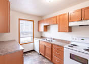Thumbnail 20 of 28 - A kitchen with wooden cabinets and a white stove top oven. West Fargo, ND Sheyenne Terrace Townhomes