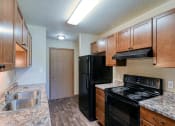 Thumbnail 5 of 12 - Grand Forks, ND Madison Apartments. A kitchen with black appliances and a closet.