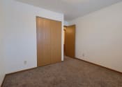 Thumbnail 6 of 10 - a bedroom with a door to a closet and a carpeted floor. Fargo, ND Alden Pines Apartments