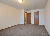 Thumbnail 7 of 10 - a spacious bedroom with carpet and a door to a hallway. Fargo, ND Alden Pines Apartments