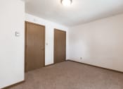 Thumbnail 5 of 6 - Bismarck, ND Arbor 400 Apartments.  A bedroom with a carpeted floor and a wooden door