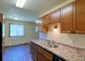 Thumbnail 6 of 12 - Grand Forks, ND Madison Apartments. A kitchen with a window in the dining area.