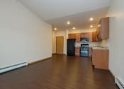 Thumbnail 11 of 23 - an empty living room with wood flooring and a kitchen. Fargo, ND North Sky Apartments