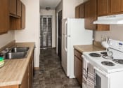 Thumbnail 3 of 7 - Grand Forks, ND Barrette Arms Apartments. a kitchen with white appliances and wooden cabinets