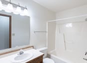 Thumbnail 18 of 19 - a bathroom with a shower sink and mirror and a toilet. Fargo, ND Rosegate Apartments