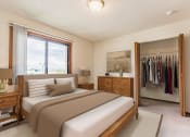 Thumbnail 5 of 14 - Bismarck, ND Eagle Sky I. A bedroom with a bed and a wardrobe. Bright natural light fills the room from a large window at the head of the bed.