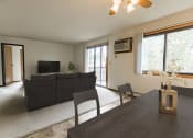 Thumbnail 2 of 14 - Bismarck, ND Eagle Sky I. A dining room with a black table with four chairs. The glass sliding door in the background brightens the room and living room behind the table with natural light.