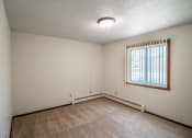 Thumbnail 13 of 16 - A bedroom with carpeted floors and a window. Bismarck, ND Eastbrook Apartments.