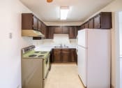 Thumbnail 11 of 16 - A kitchen with white appliances and brown cabinets and a refrigerator. Bismarck, ND Eastbrook Apartments .