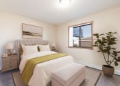 Thumbnail 6 of 13 - Bismarck, ND Fairview Apartments. A bedroom that showcases a comfortable bed with neatly arranged bedding, a stylish bed bench, and a window that fills the space with natural light. It's a serene and inviting setting for rest and relaxation.