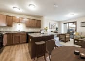 Thumbnail 5 of 13 - Bismarck, ND Fairview a combined dining and living area with dark wood cabinets and furnishings. The space features a dining table, chairs, and comfortable seating for the living room. It offers a versatile and inviting area for dining, relaxation, and socializing with family and friends