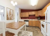 Thumbnail 2 of 13 - Bismarck, ND Fairview. A Kitchen that showcases appliances, a dining table with chairs, and a bold red accent wall. It's a stylish and inviting area for cooking and enjoying meals.