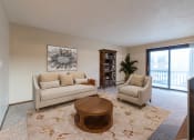Thumbnail 2 of 10 - Bismarck, ND Newgate Apartment a living room with a large rug, couch, and tv. A glass sliding door brightens the room with natural light