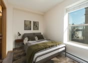Thumbnail 3 of 4 - Bismarck, ND Norma Apartment serene bedroom featuring olive green bedding and a small window. The room exudes a tranquil ambiance