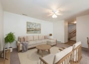 Thumbnail 1 of 11 - Bismarck Pebble Creek Apartments. The spacious living room is tastefully decorated with stylish furniture, ample natural light, and a cozy atmosphere. There's overhead lighting with a touch of natural light from the dining room. Access to the upstairs is in the background