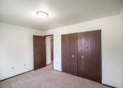 Thumbnail 13 of 17 - Bismarck, ND Rosser Apartments. a bedroom with two doors and a carpeted floor
