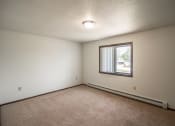 Thumbnail 12 of 17 - Bismarck, ND Rosser Apartments. a bedroom with a large window and beige carpet